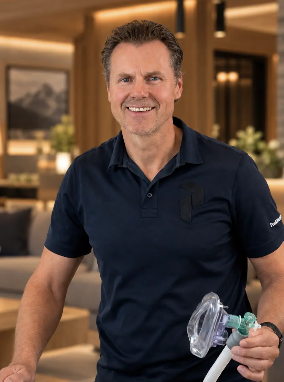 Stefan Brammen lächelt in einer Hotellobby und hält eine Atemmaske in der Hand